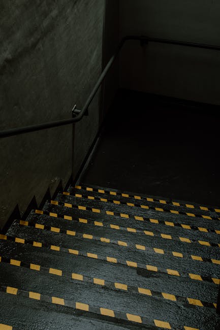 A multi-storey residential building exterior during the home relocation process, showing an external metal staircase with black railings leading from the pavement to a rear door on the first floor. Th